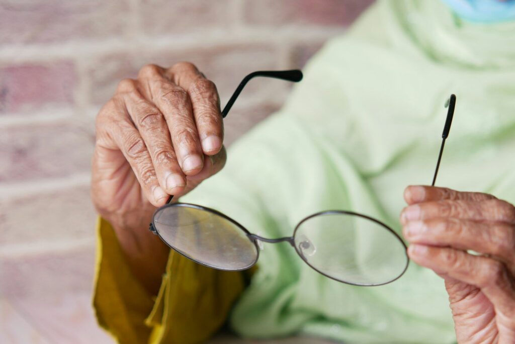 an elderly woman holding a pair of glasses